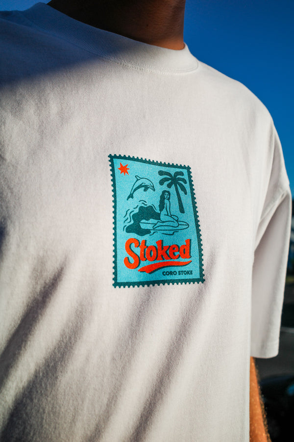 The new Coro Stoke Stamo Minus tee with the colorful graphic design on the front against a blue sky.