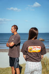 Two people standing on a beach and both are wearing the new Wave Therapy T-Shirt from Coro Stoke.
