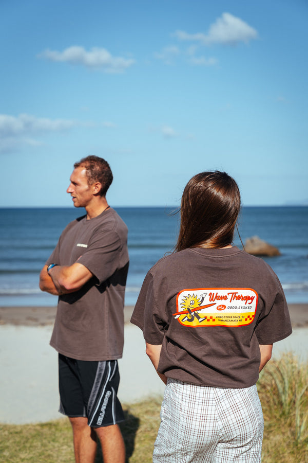 Two people standing on a beach and both are wearing the new Wave Therapy T-Shirt from Coro Stoke.