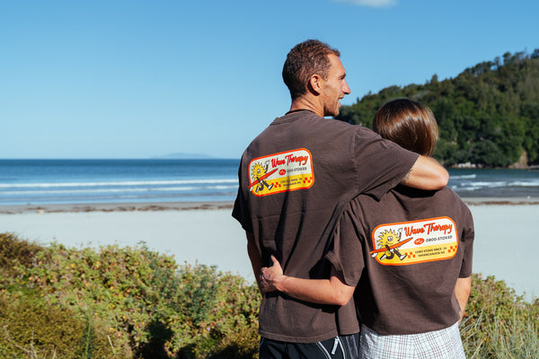 Two people wearing the new Wave Therapy T-Shirt from Coro Stoke in brown on a beach.