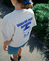 Women wearing a t-shirt with 'Waves for Dinner' graphic design outdoors.