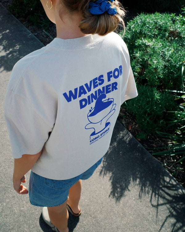 Women wearing a t-shirt with 'Waves for Dinner' graphic design outdoors.